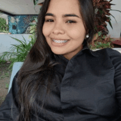 Arley Del Carmen Gómez Ureña smiling at the camera against a tropical background.